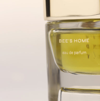 Close-up of Bee's Home eau de parfum bottle with golden cap and golden fragrance liquid, luxury niche perfume for men and women.